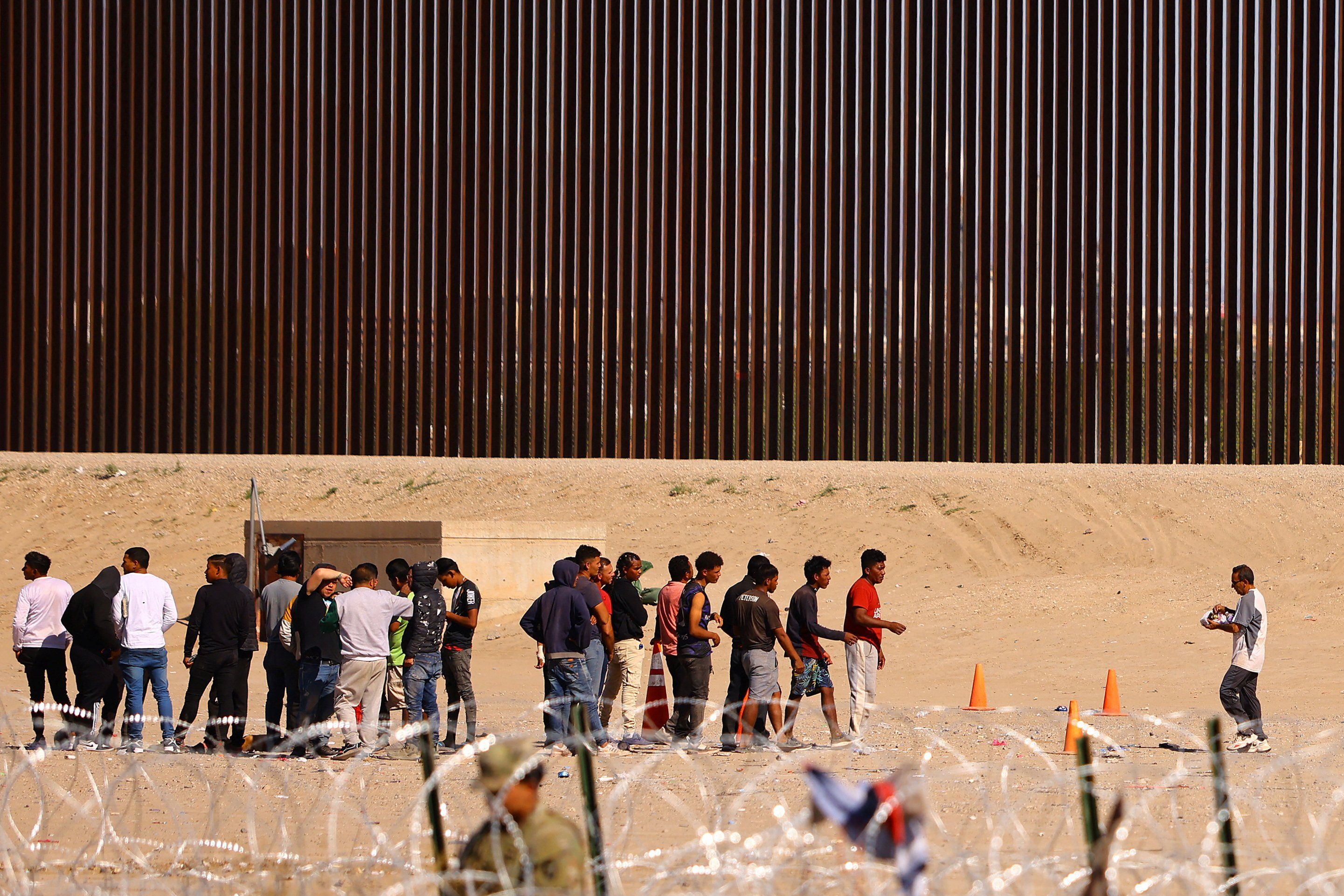 Migrants gather near the border wall