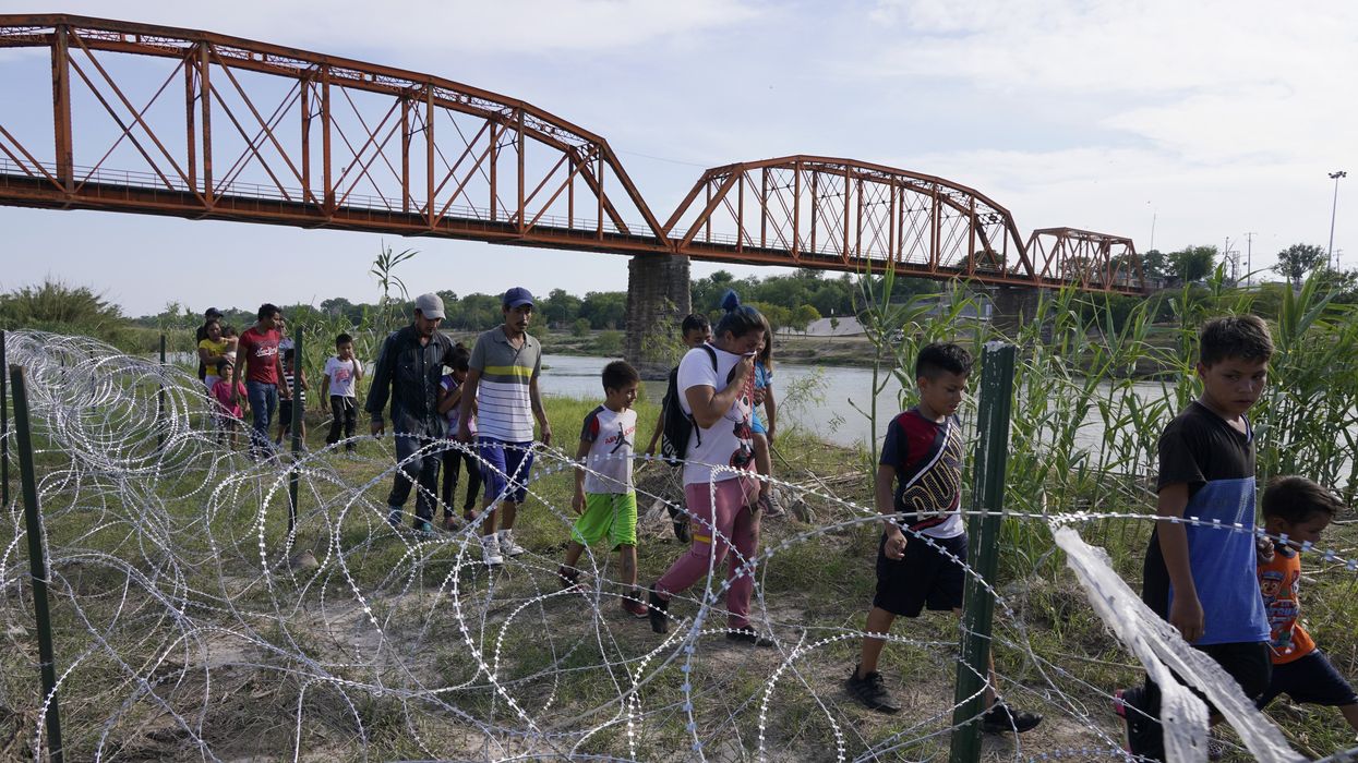 Migrants, most with children follow a path along the concertina wire where ultimatley they will placed under guard by Border Patrol after having crossed the Rio Grande on May 27 2022 in Eagle Pass Texas, USA. Title 42, the Trump era mandate which was set to prevent migrants from entering the US, was to expire on May 23 but was blocked by a lawsuit filed by several states citing that the move to strike down the law “failed to meet standards set by the Administrative Procedure Act” and that there is no permanent solution to handling the inevitable surge in immigration. Opponents to upholding of the law voiced their demands stating that Title 42 is illegal in that it violates immigration laws that prevents immigrants from their right to seek asylum. Since the implementation of Title 42 in March 2020, US Customs and Border Protection has effected “more than 1.8 million expulsions, mostly on the southern border of the US-Mexico Border”.