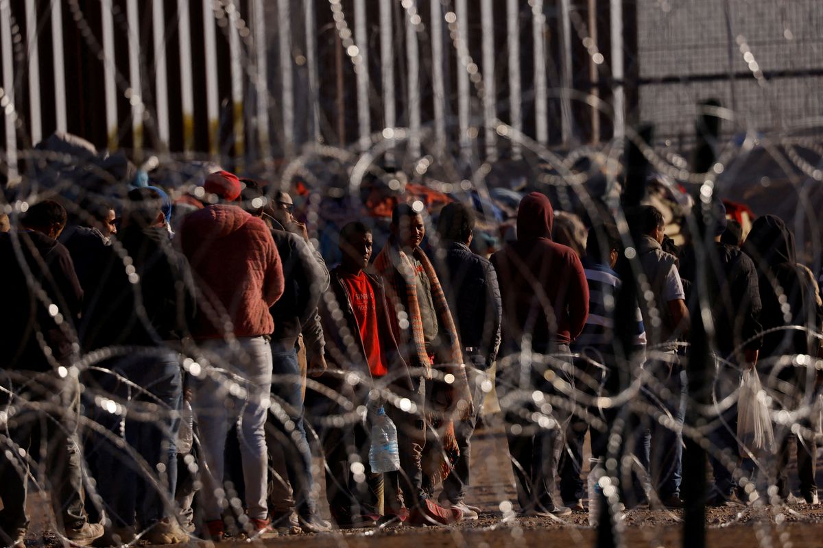 Migrants stand near the border wall after having crossed into the US from Ciudad Juarez, Mexico.