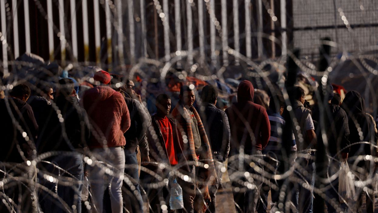 Migrants stand near the border wall after having crossed into the US from Ciudad Juarez, Mexico.