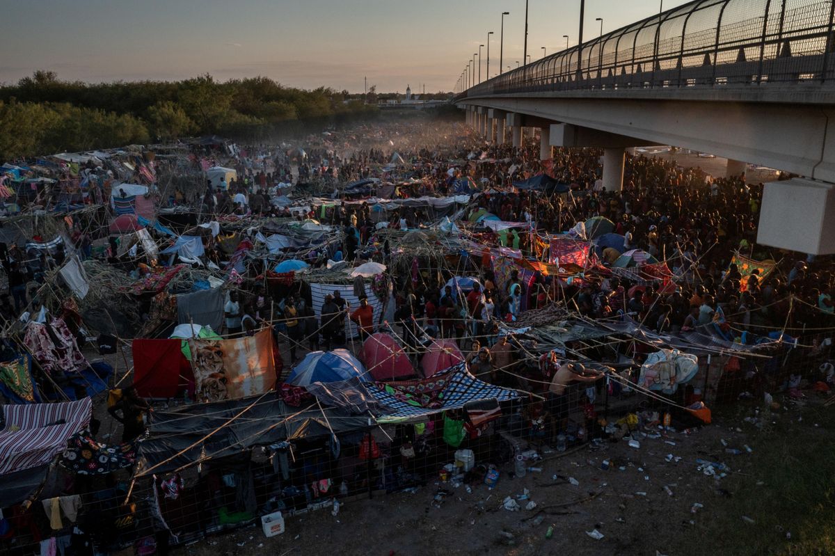 Migrants take shelter along the Del Rio International Bridge at sunset as they await to be processed after crossing the Rio Grande river into the U.S. from Ciudad Acuna in Del Rio, Texas, U.S. September 19, 2021.