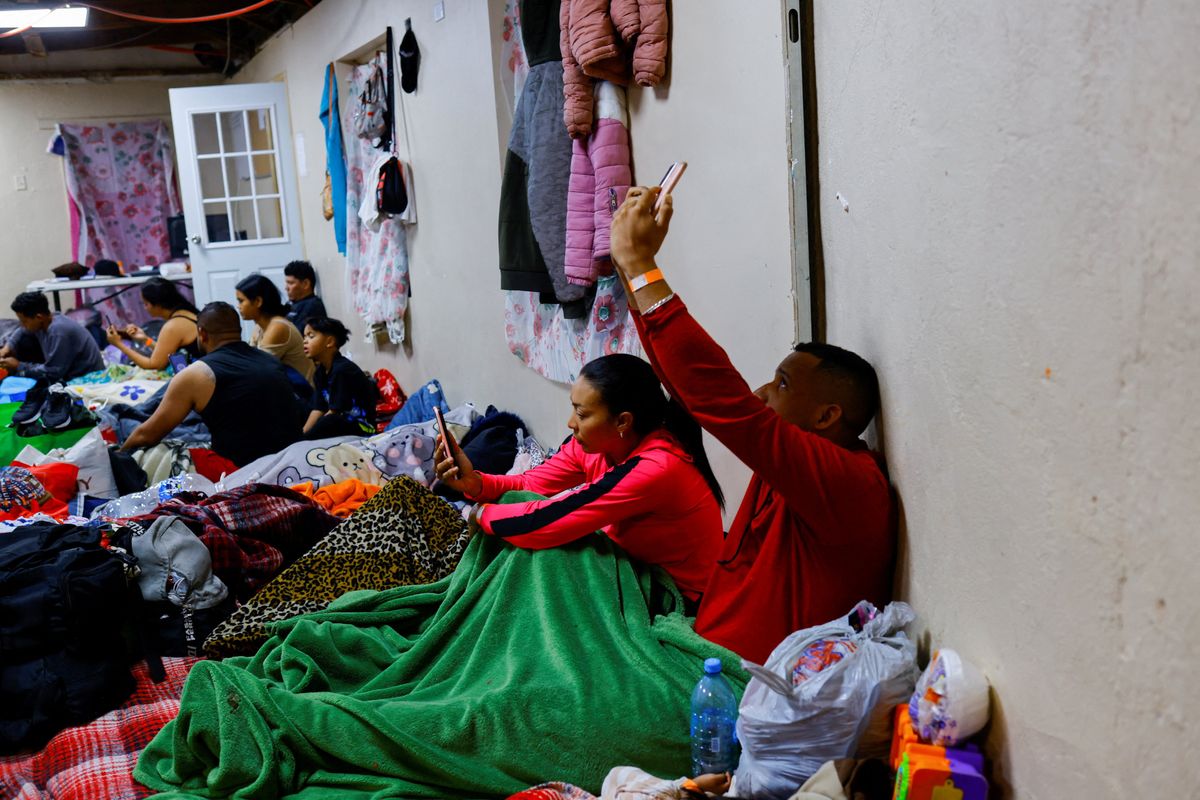 Migrants use their phones to access the U.S. Customs and Border Protection (CBP) in a shelter near the US-Mexico border in Ciudad Juarez, Mexico February 24, 2023.