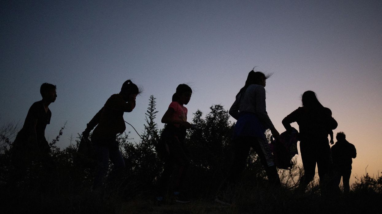Migrants walk along a dirt trail after crossing the Rio Grande river into the US from Mexico in Roma, Texas.