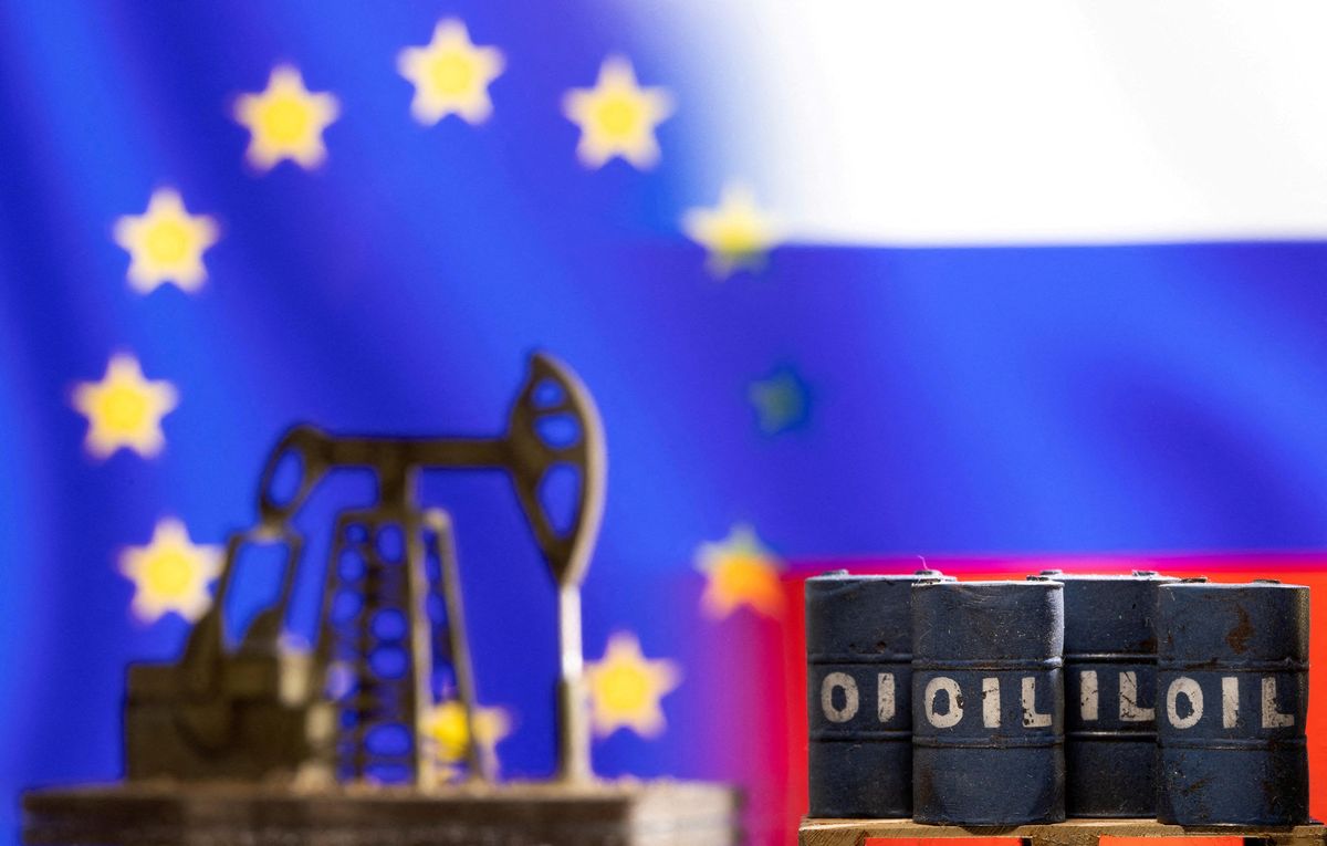 Models of oil barrels and a pump jack are seen in front of displayed EU and Russia flags colors.