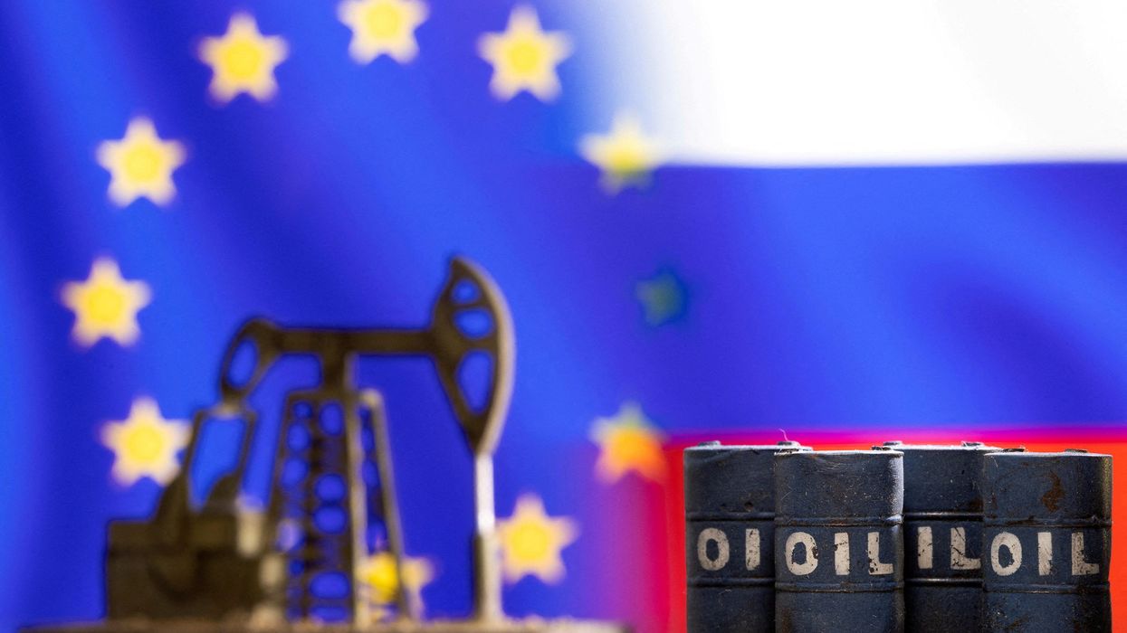 Models of oil barrels and a pump jack are seen in front of displayed EU and Russia flags colors.