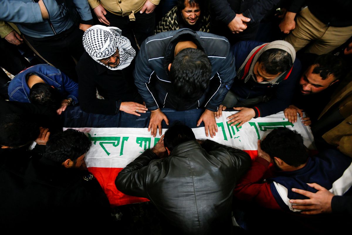 Mourners gather near the coffin of a man, who was killed in a twin suicide bombing attack in a central Baghdad market, during a funeral in Najaf, Iraq, January 21, 2021.