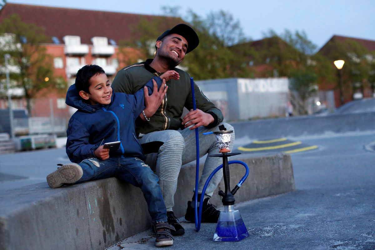 Mudasir Khan, originally from Pakistan, sits with his nephew Yaeesh Rao Khan in Mjolnerparken, a housing estate that features on the Danish government's "Ghetto List"