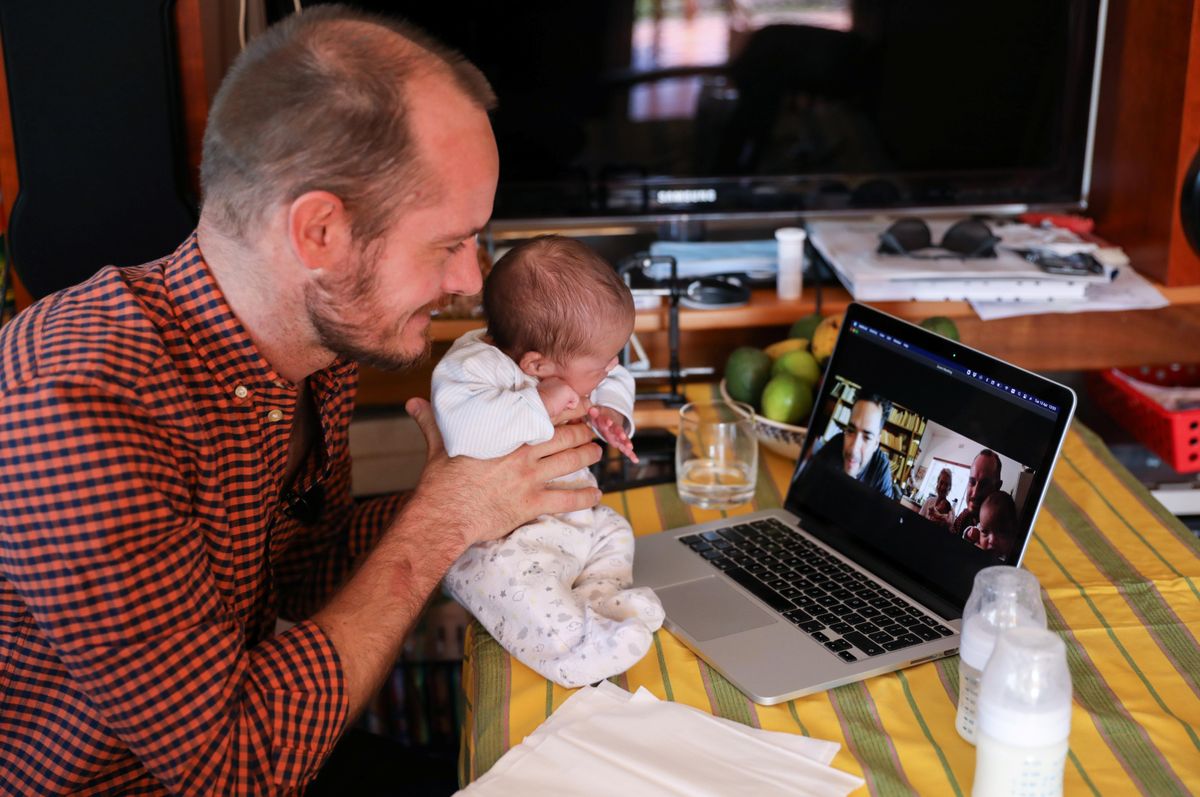 Namibian citizen Phillip Luhl holds one of his twin daughters as he speaks to his Mexican husband Guillermo Delgado via Zoom meeting in Johannesburg, South Africa, April 13, 2021