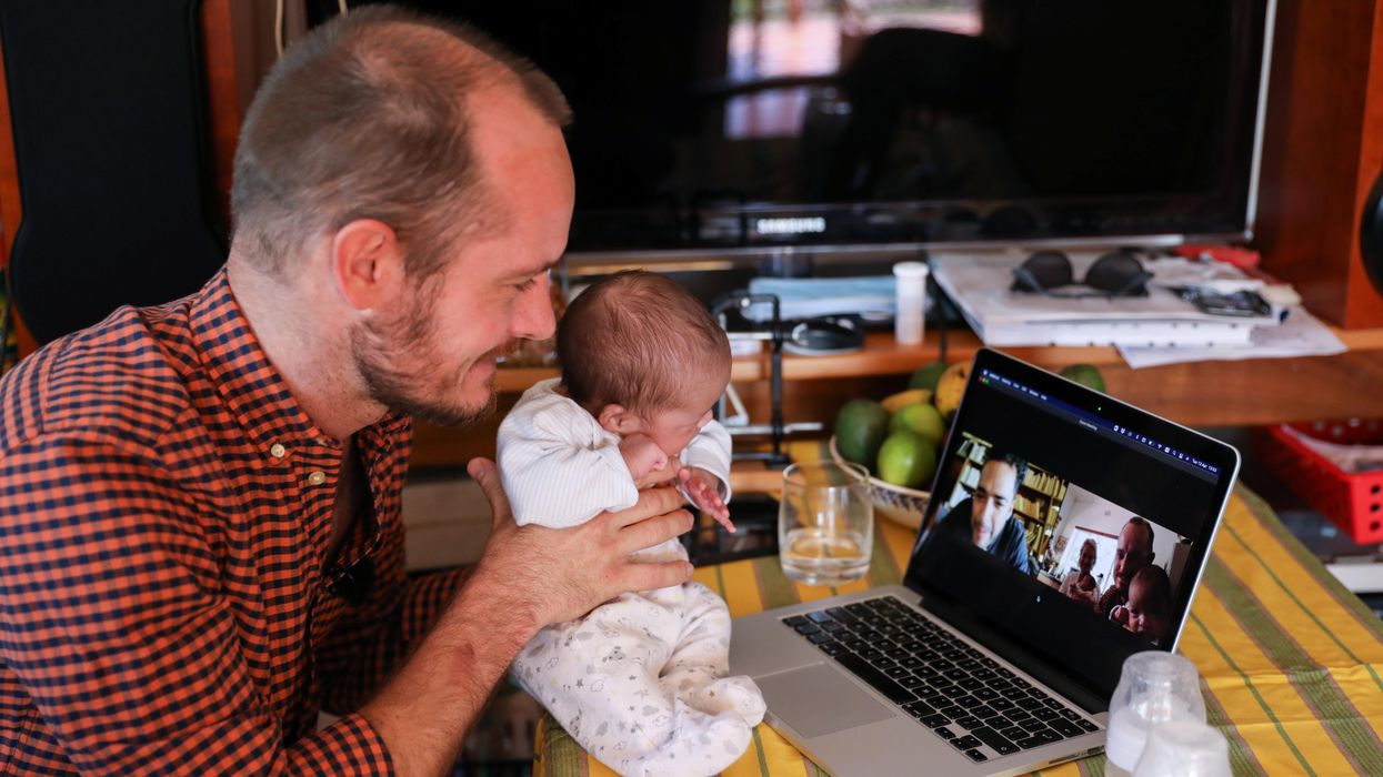 Namibian citizen Phillip Luhl holds one of his twin daughters as he speaks to his Mexican husband Guillermo Delgado via Zoom meeting in Johannesburg, South Africa, April 13, 2021
