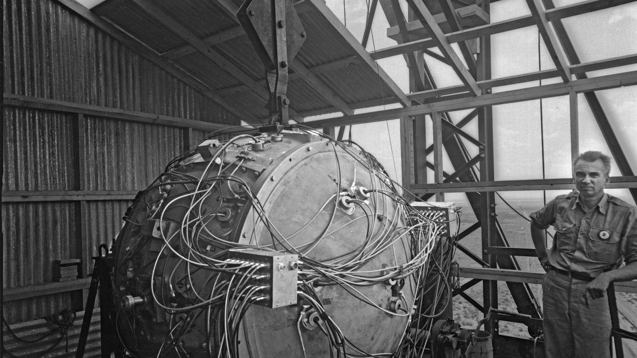 Norris Bradbury, group leader for bomb assembly, stands next to the partially assembled Gadget atop the test tower at Los Alamos in 1945.