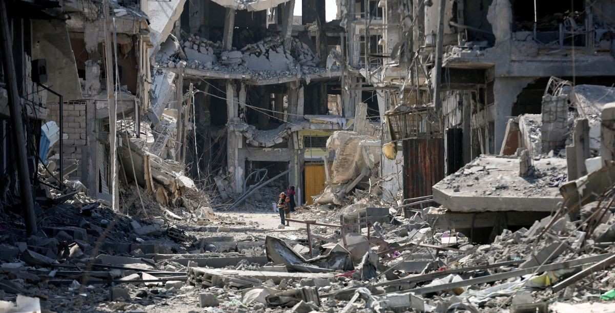 ​Palestinian children look at rubble following Israeli forces' withdrawal from the area, after Israel and Hamas agreed on the Gaza ceasefire, in Khan Younis, in the southern Gaza Strip, October 10, 2025. 