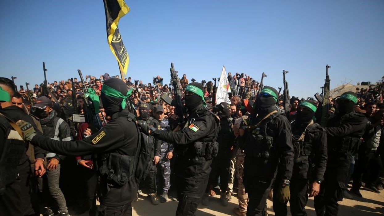 Palestinian Hamas and Islamic Jihad fighters form a human chain in front of the crowd gathered near the family home of slain Hamas leader Yahya Sinwar, where the Hamas militant group prepares to hand over Israeli and Thai hostages to a Red Cross team in Khan Yunis, on January 30, 2025, as part of their third hostage-prisoner exchange..