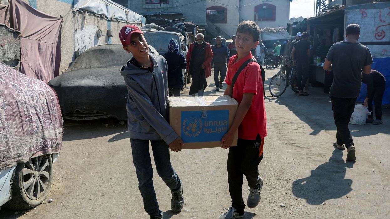 Palestinians carry an aid box distributed by the United Nations Relief and Works Agency (UNRWA), amid the Israel-Hamas conflict, in Deir Al-Balah, central Gaza Strip, November 4, 2024.