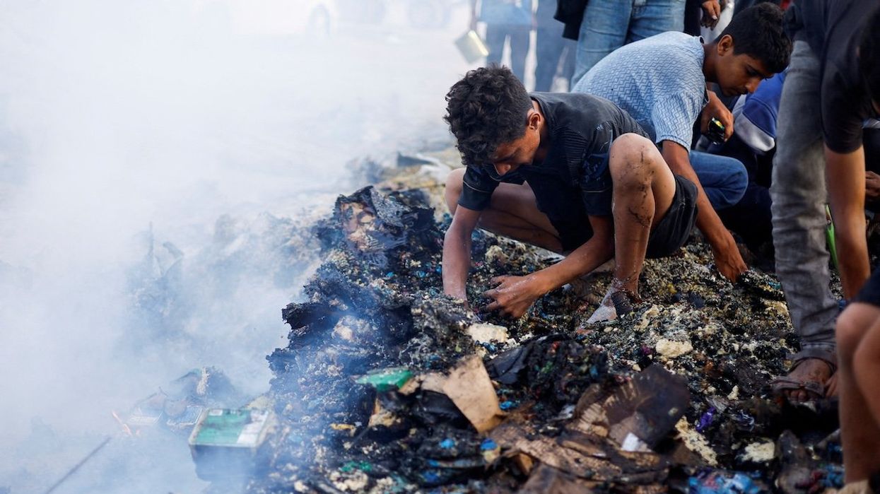 Palestinians search for food among burnt debris in the aftermath of an Israeli strike on an area designated for displaced people, in Rafah in the southern Gaza Strip, on May 27, 2024.