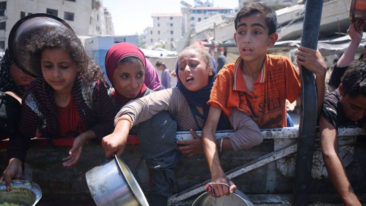 Palestinians wait to receive food from a charity kitchen in Gaza City, on August 27, 2025.