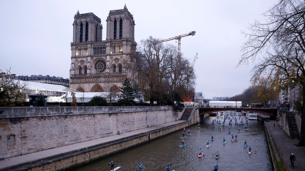 Participants make their way past the Notre-Dame Cathedral as they attend the 13th edition of the stand up Nautic Paddle race on the river Seine in Paris, France, December 1, 2024.