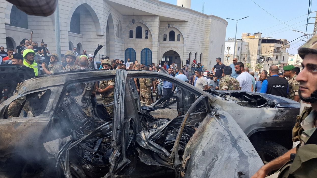 People and Lebanese army members stand near a burnt car after an Israeli strike on the outskirts of the southern port city of Sidon, according to two Palestinian sources, in Lebanon August 21, 2024.