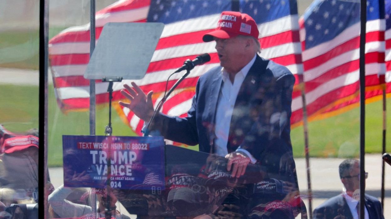 People are reflected in protective glass as they listen to Republican presidential nominee and former U.S. President Donald Trump as he speaks during a rally in Mosinee, Wisconsin, U.S. September 7, 2024.