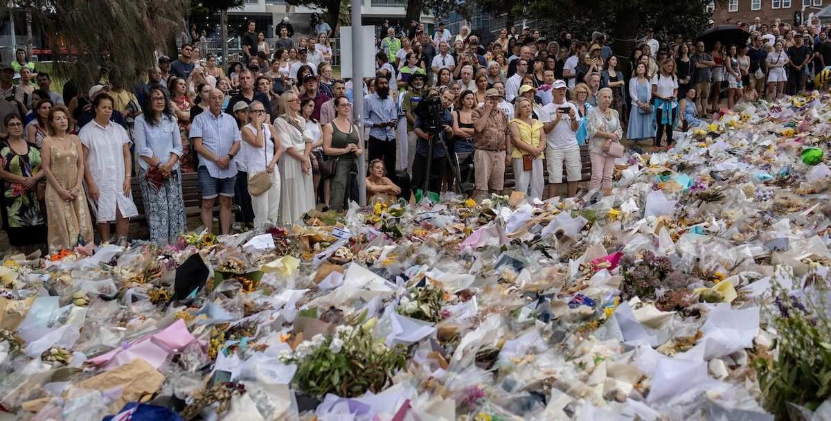 People gather around offered flowers to honour the victims of a mass shooting during a Jewish Hanukkah celebration at Bondi Beach on December 14, in Sydney, Australia, December 19, 2025. 
