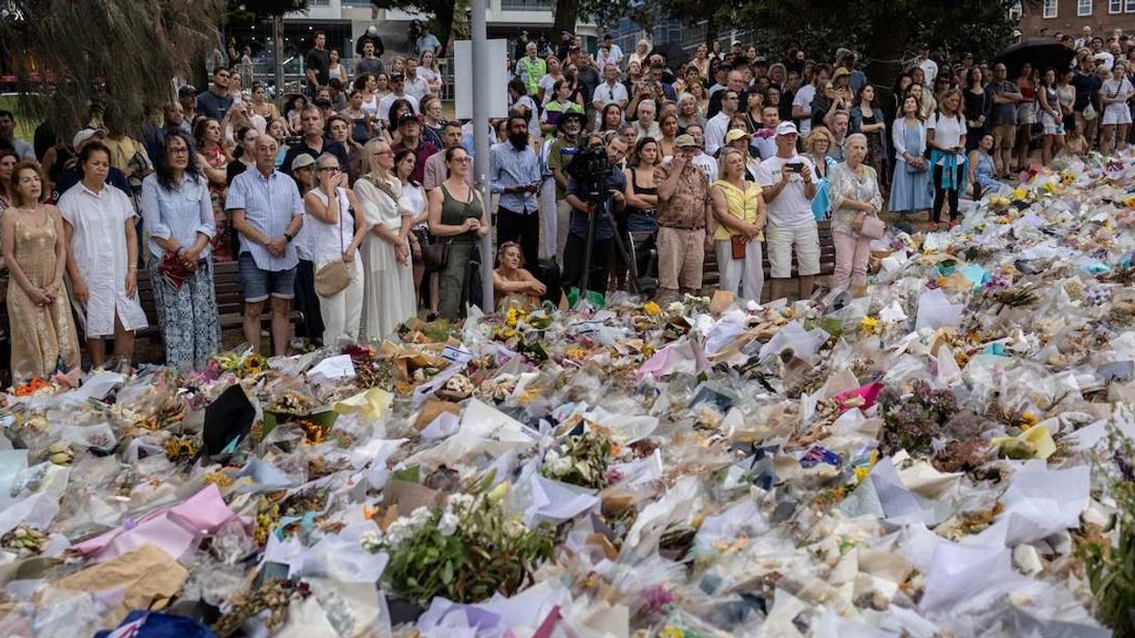 People gather around offered flowers to honour the victims of a mass shooting during a Jewish Hanukkah celebration at Bondi Beach on December 14, in Sydney, Australia, December 19, 2025.