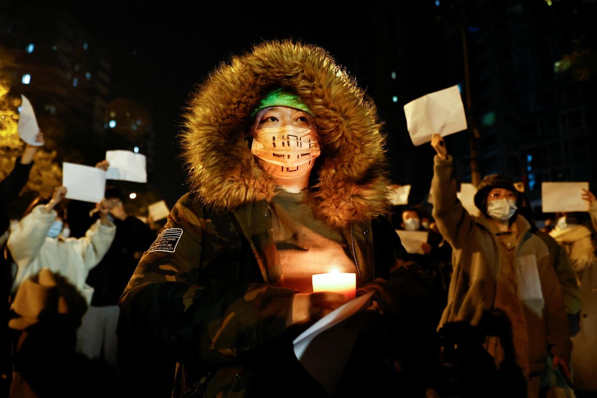People gather for a vigil and hold white sheets of paper to protest COVID restrictions in Beijing, China.