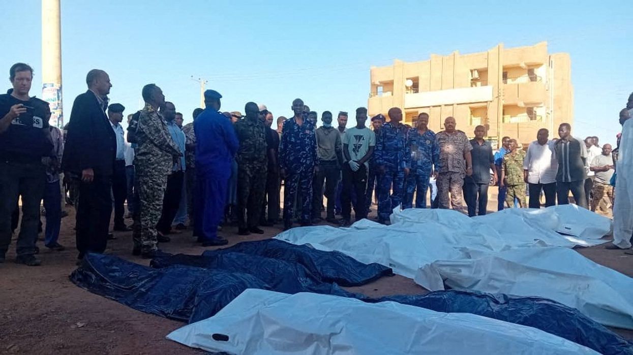 People gather next to covered bodies, following shelling by the Rapid Support Forces, in Omdurman, Sudan, December 10, 2024.