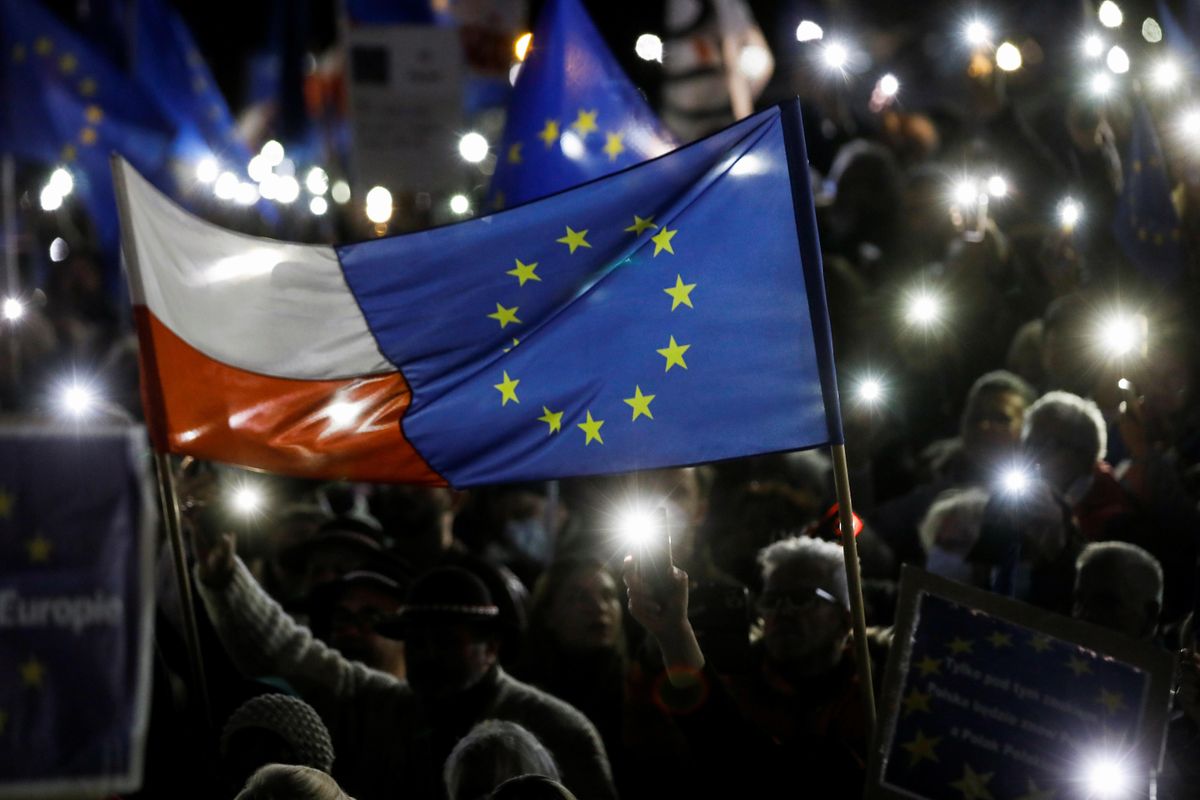 People hold flags and light up their mobile phones during a rally in support of Poland's membership in the European Union after the country's Constitutional Tribunal ruled on the primacy of the constitution over EU law, undermining a key tenet of European integration, in Warsaw, Poland, October 10, 2021. 