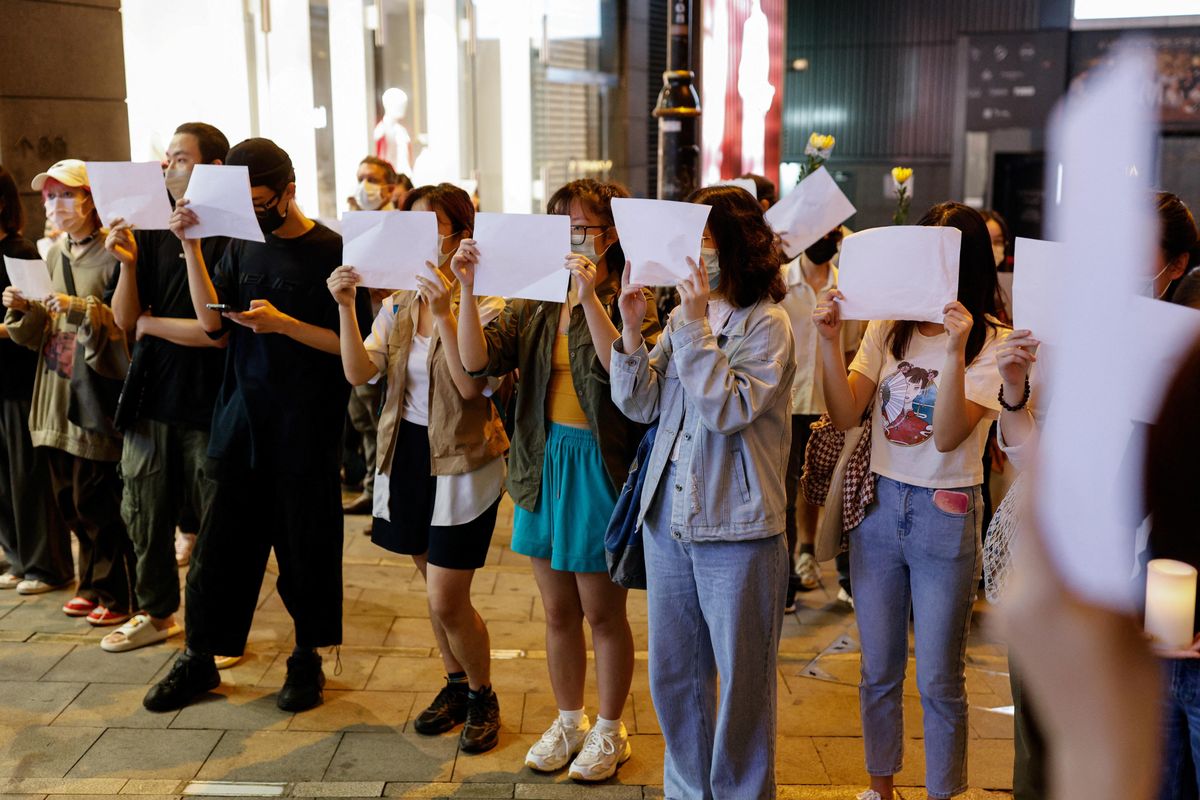 ​People in Hong Kong hold sheets of paper in protest over coronavirus disease restrictions in mainland China. 