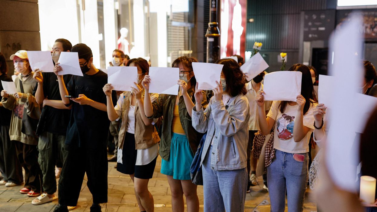 People in Hong Kong hold sheets of paper in protest over coronavirus disease restrictions in mainland China.