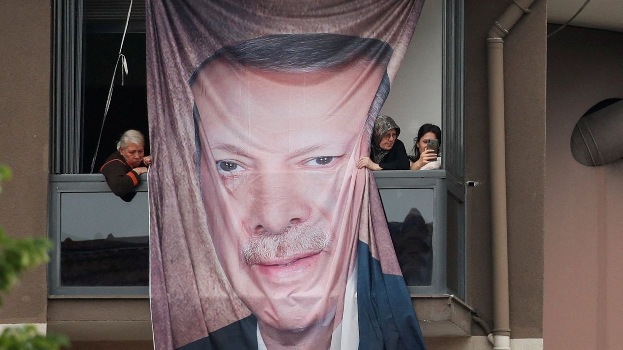 People look on from a balcony with a banner with the image of Turkish President Tayyip Erdogan.