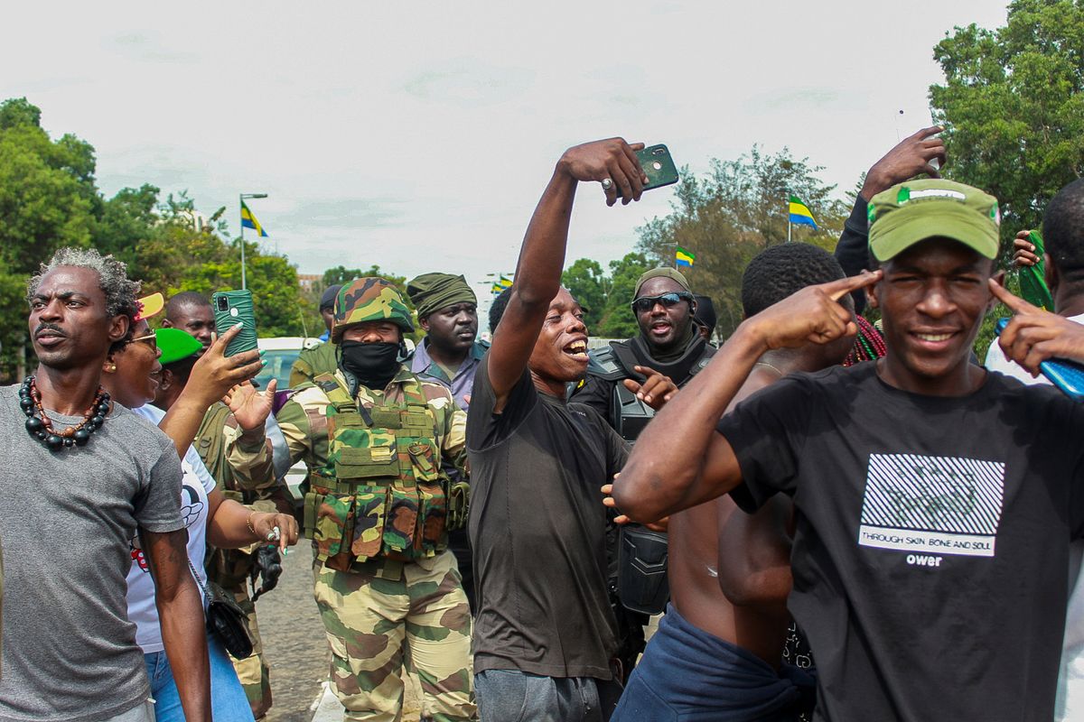 People pose with soldiers as they celebrate in support of the putschists in a street of Libreville, Gabon.