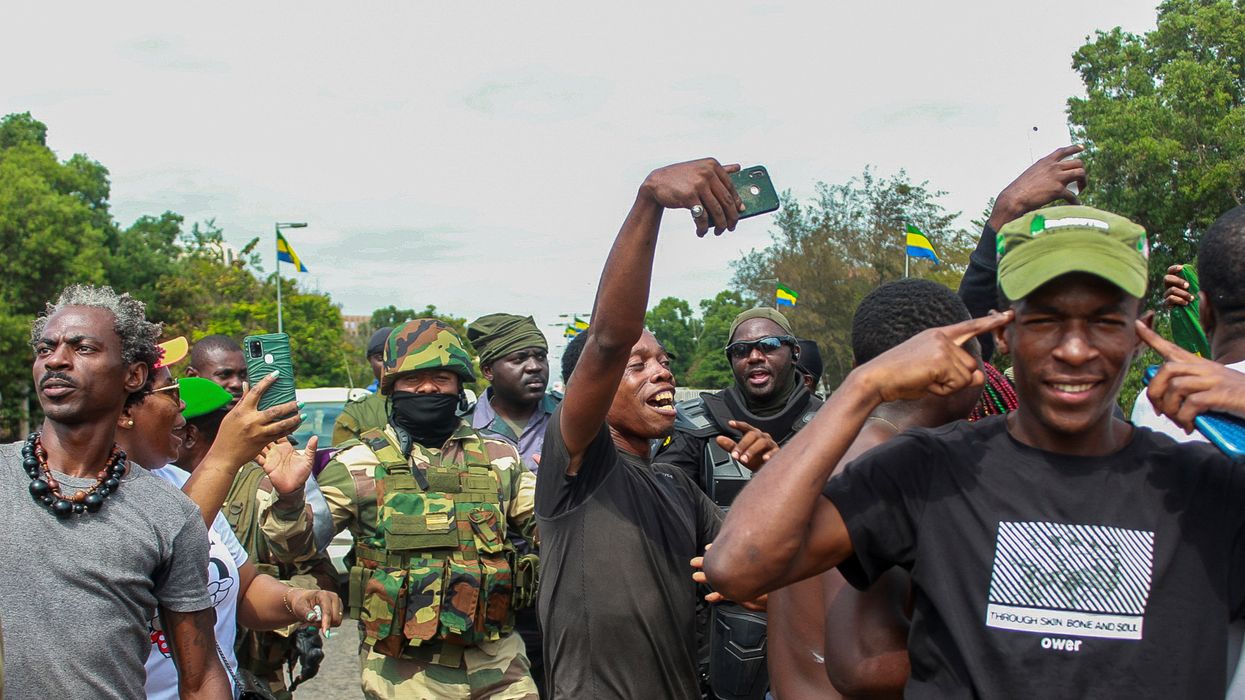 People pose with soldiers as they celebrate in support of the putschists in a street of Libreville, Gabon.