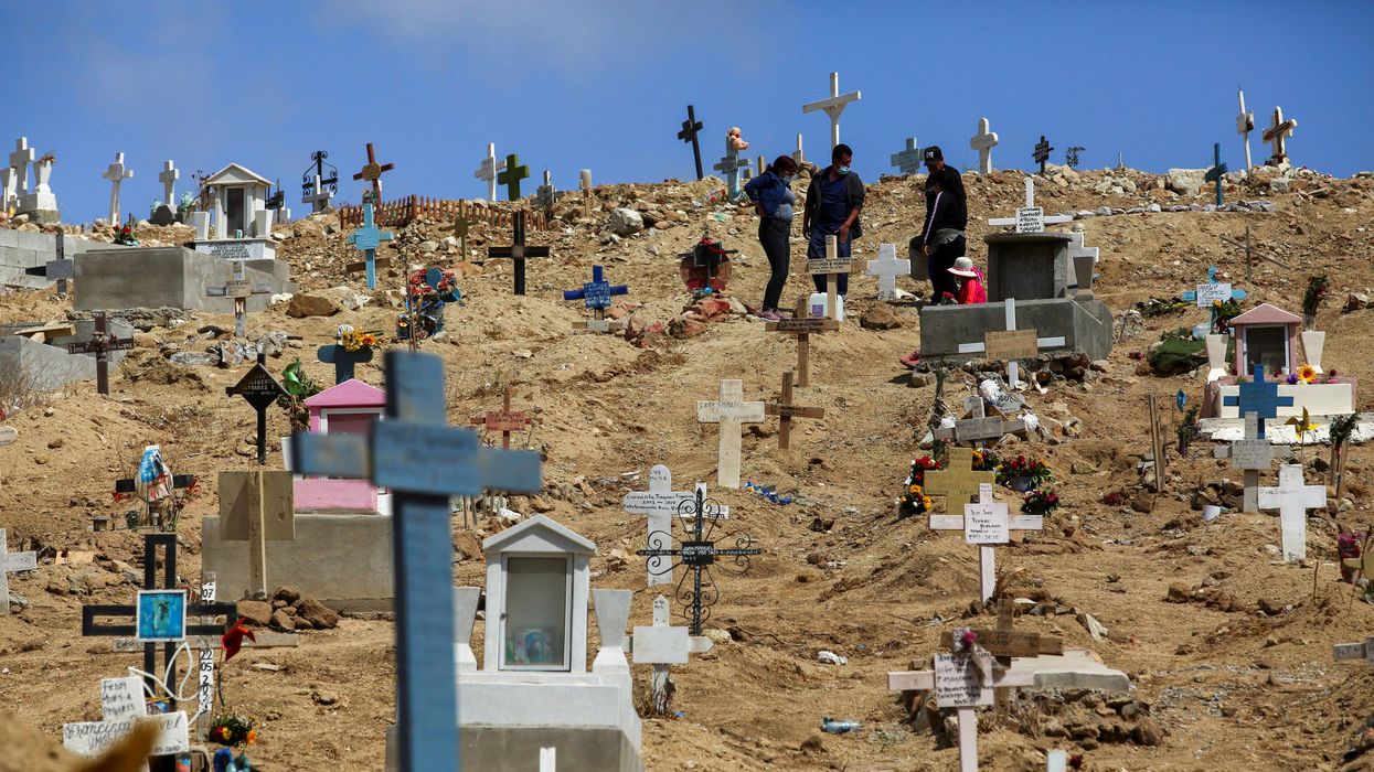 People stand among graves of victims of the coronavirus disease (COVID-19), and of others, at the municipal cemetery No. 12 in Tijuana, Mexico May 21, 2021