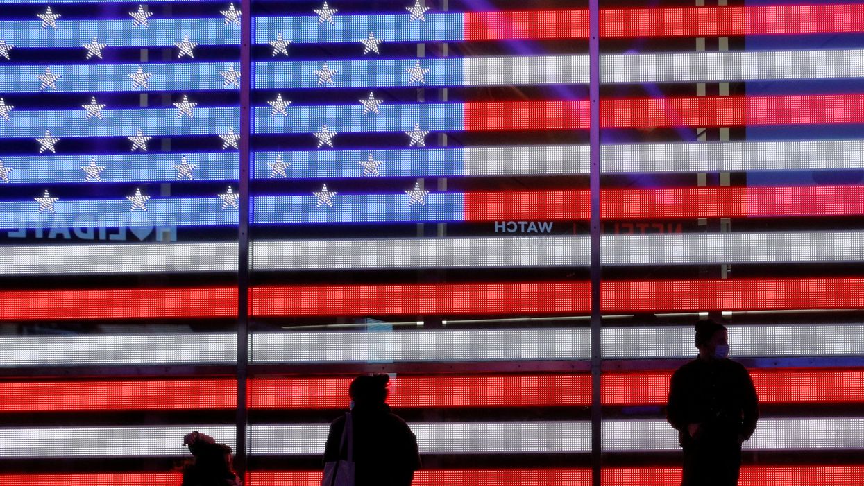 People stand next to a screen displaying a U.S. flag in Times Square during the 2020 U.S. presidential election in New York City, New York, U.S. November 4, 2020.