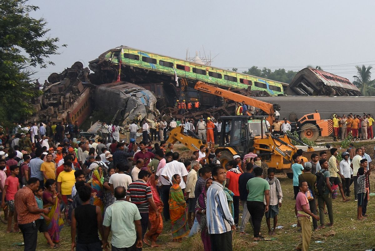 People stand next to damaged coaches after two passenger trains collided in Balasore district in the eastern state of Odisha, India.