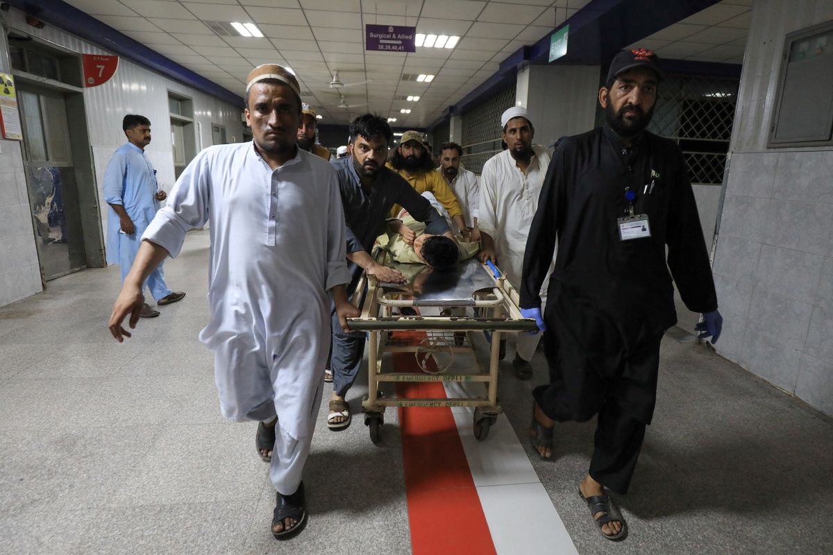 ​People transport a man injured by a blast in Bajaur, Pakistan, on Sunday.
