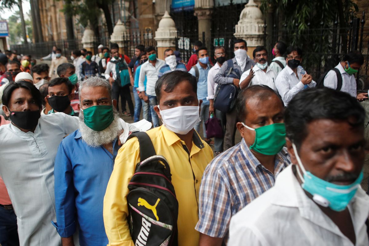 People wait in line to board a bus amidst the spread of the coronavirus disease (COVID-19) in Mumbai