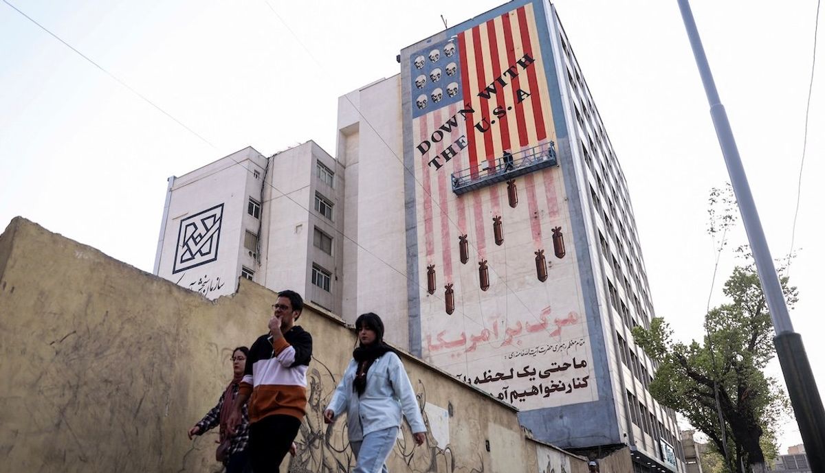 ​People walk by as a painter repaints an anti-US mural in Tehran, Iran, on Saturday, March 29, 2025.