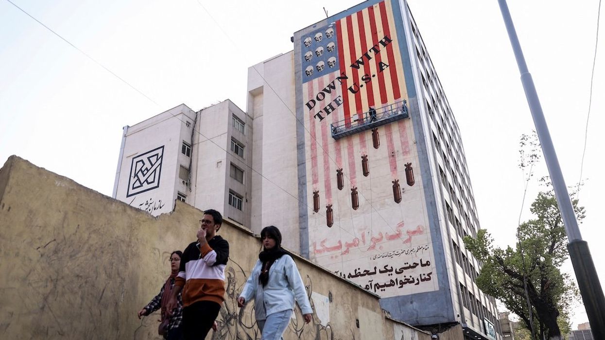 People walk by as a painter repaints an anti-US mural in Tehran, Iran, on Saturday, March 29, 2025.