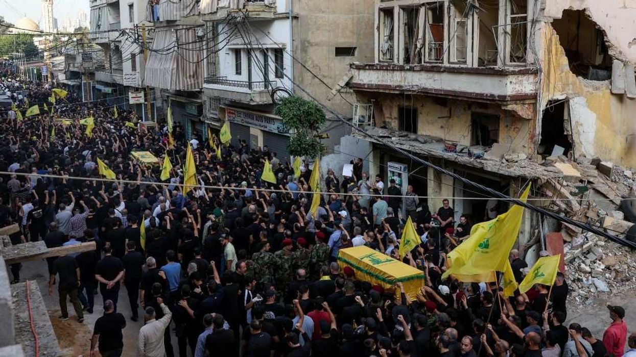 People walk past a damaged building during the funeral of Hezbollah's top military official, Haytham Ali Tabtabai, and of other people who were killed by an Israeli airstrike on Sunday, despite a U.S.-brokered truce a year ago, in Beirut's southern suburbs, Lebanon November 24, 2025.