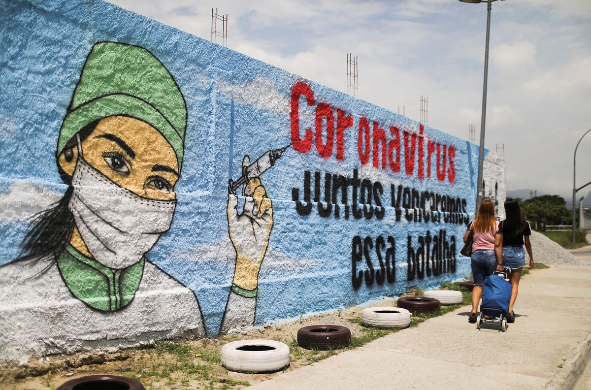 People walk past a graffiti amidst the spread of the coronavirus disease (COVID-19) in Rio de Janeiro, Brazil March 12, 2021. The graffiti reads: "Coronavirus, together we will win that battle".