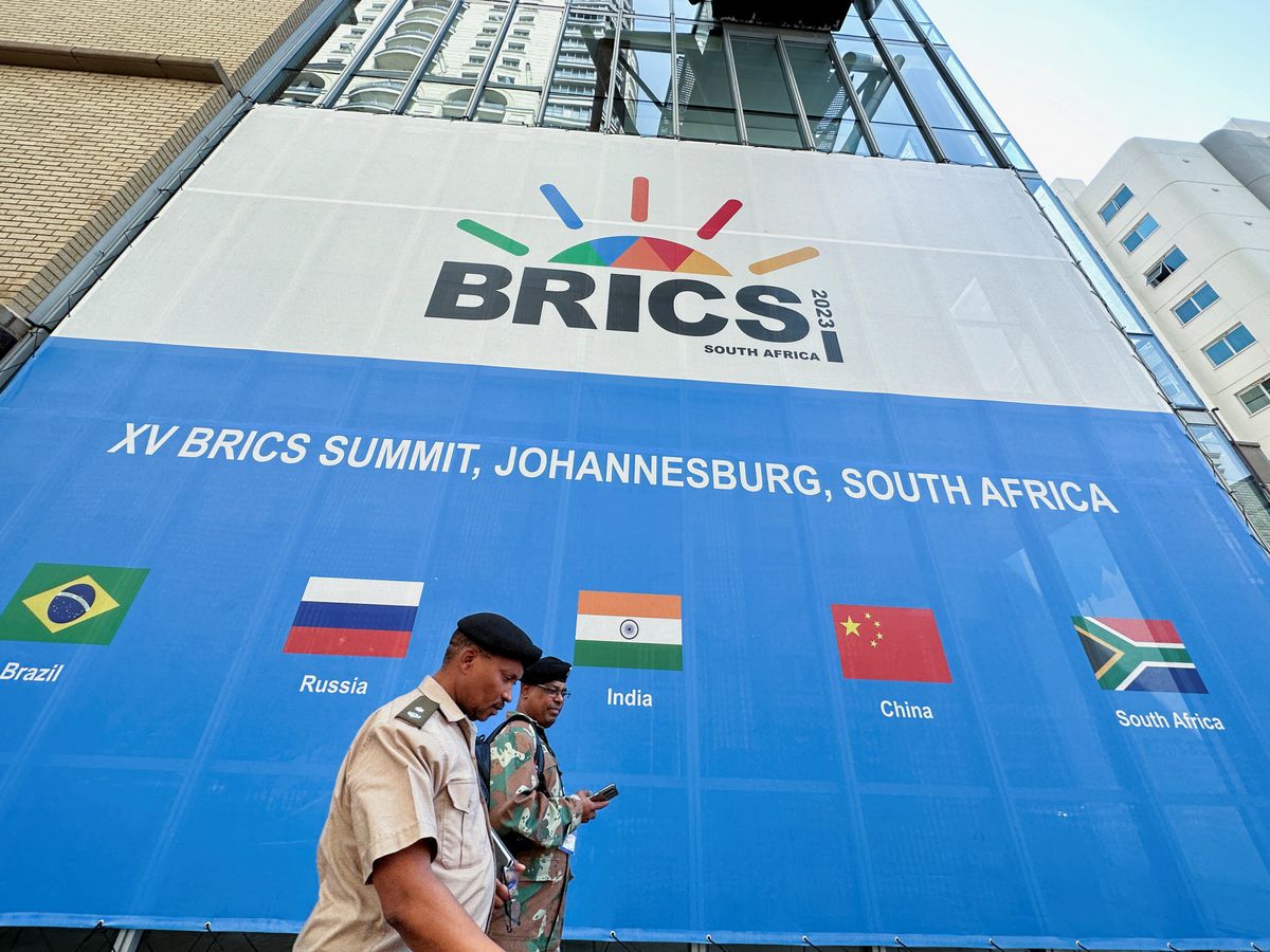 ​People walk past the Sandton Convention Centre, where the BRICS Summit is being held in Johannesburg, South Africa. 