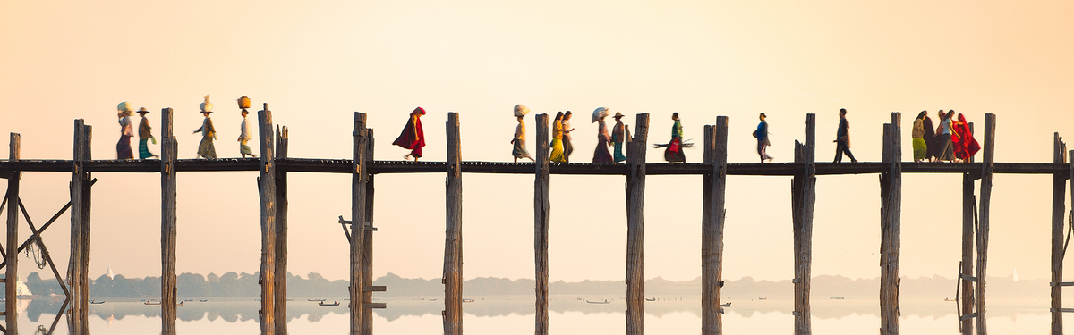 People walking along a bridge with the horizon shown faintly in the background