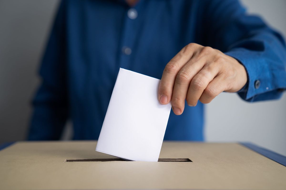 Person putting a paper in the ballot box