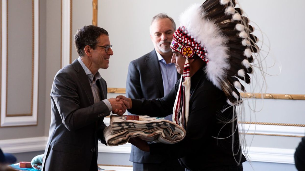 Person shaking hands and receiving a present from another Indigenous person