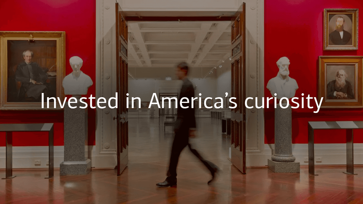 Person walking in a museum with "Invested in America's curiosity" written in the centre of the image