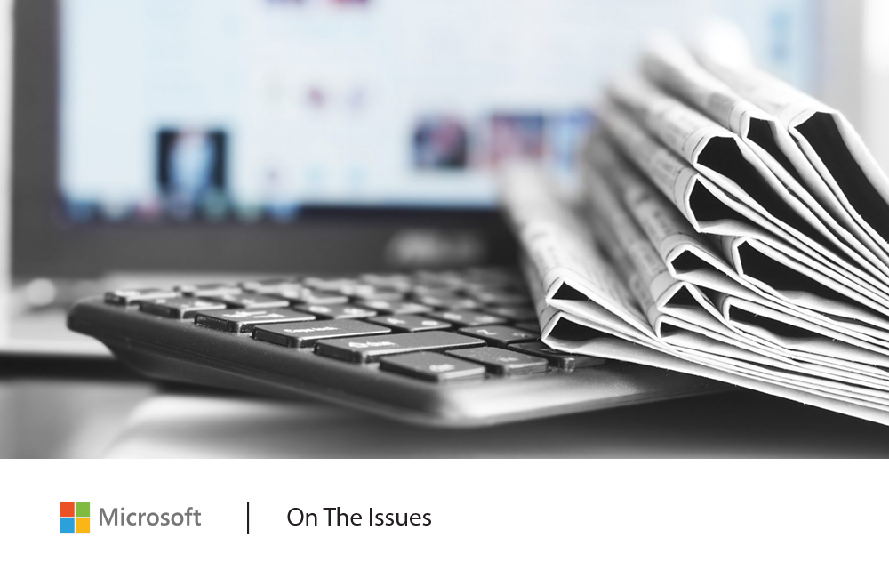 Picture of a keyboard with several newspaper sections on top. A computer screen is out of focus in the background.