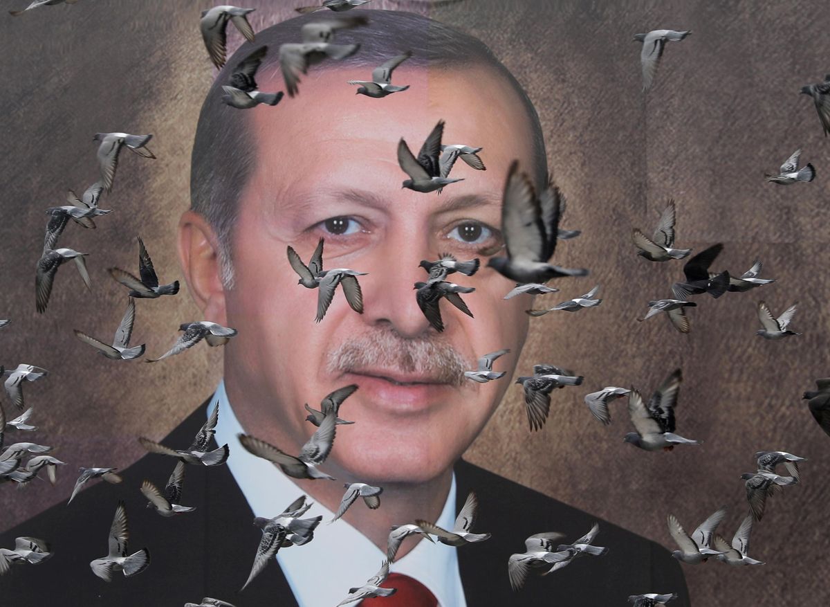Pigeons fly in front of a large poster of Turkish President Tayyip Erdogan in Bursa, Turkey, April 6, 2019.