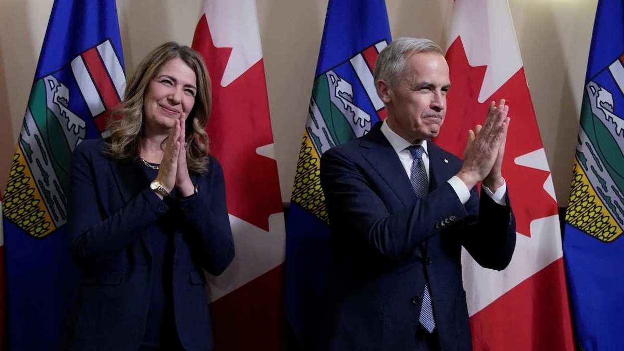 PM Carney and Alberta Premier Smith joining their hands acknowledging the crowd before signing an energy agreement