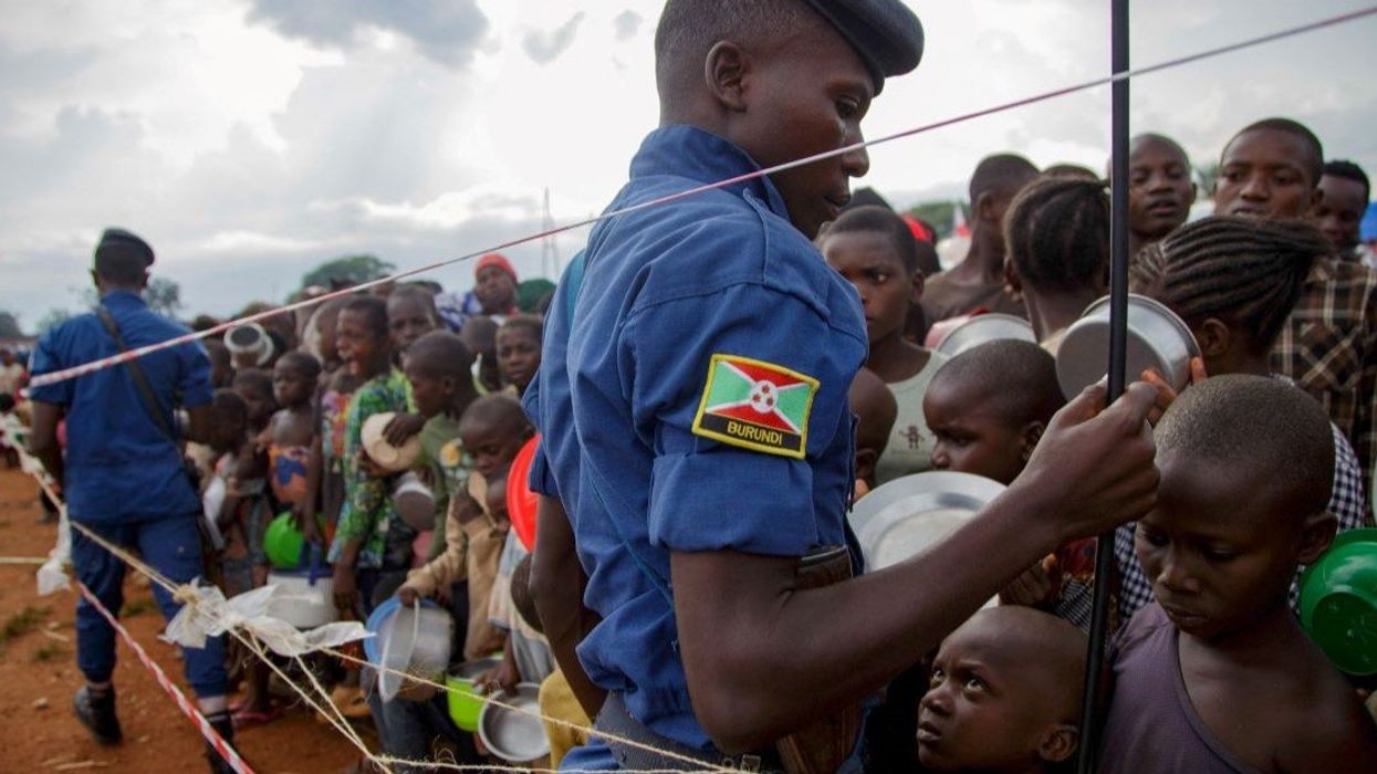 Police officers stand guard as Congolese youngsters jostle to receive relief food, after fleeing from renewed clashes between M23 rebels and the Armed Forces of the Democratic Republic of the Congo. February 18, 2025.